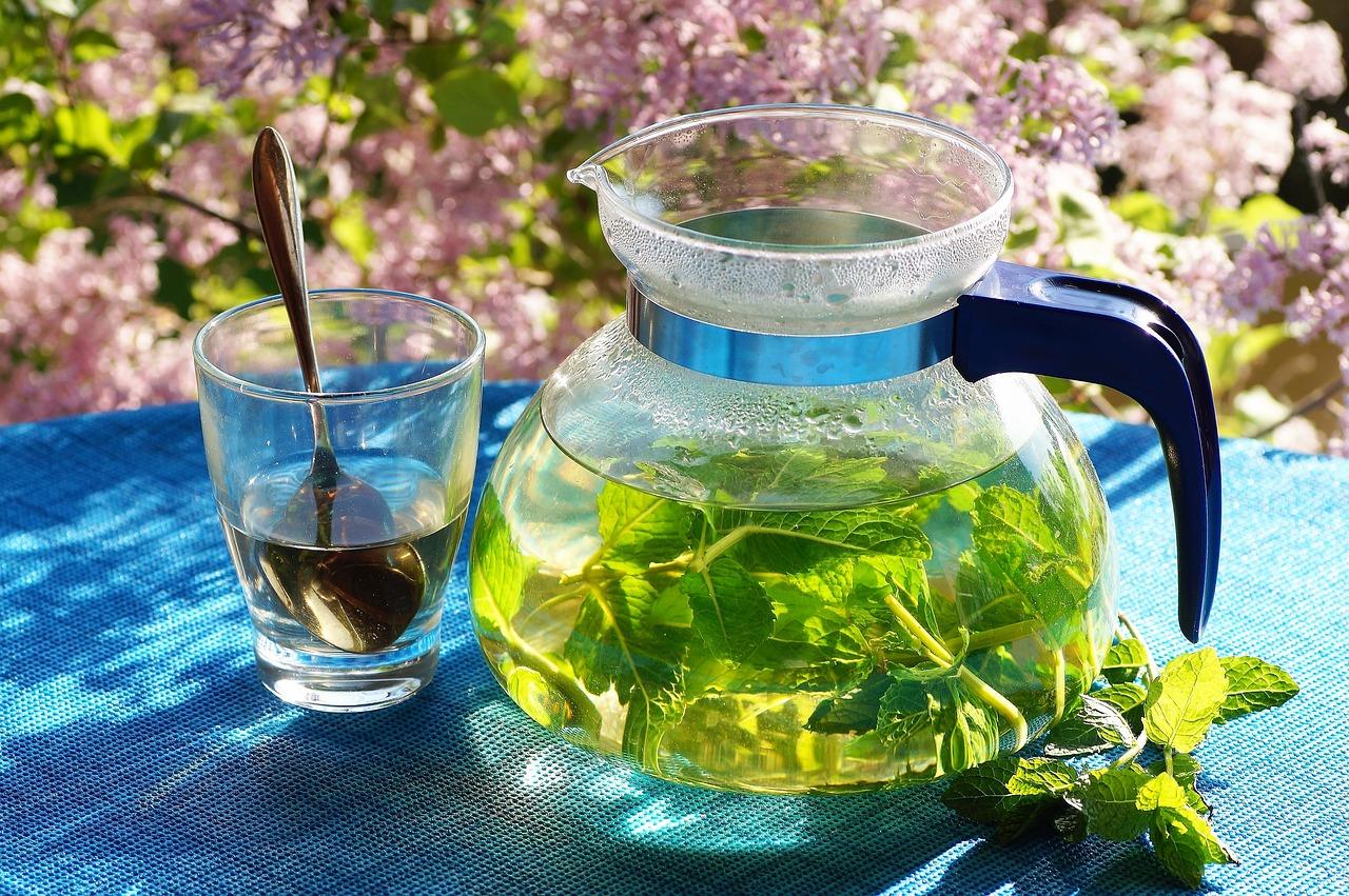Eine Kanne mit frischem Kräutertee steht auf einem Tisch und lädt zum Kosten ein.