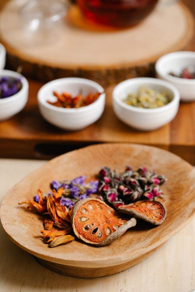 A variety of dried herbs and flowers in bowls for brewing herbal tea.