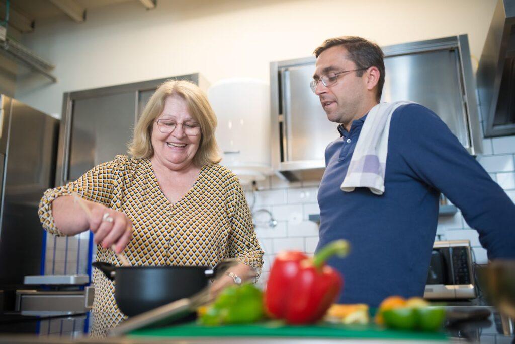 Two adults cooking together in a modern kitchen, enjoying the culinary process with fresh ingredients.